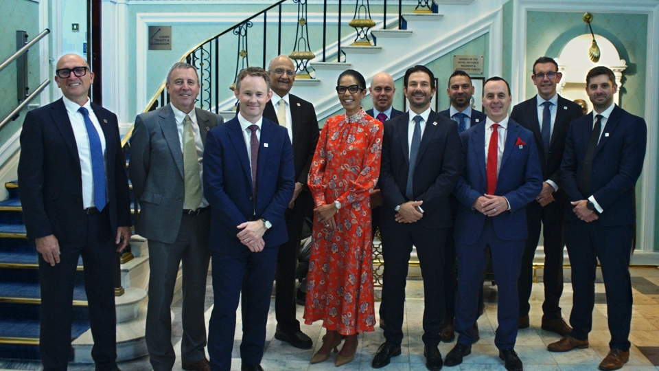 Group of Turner & Townsend professionals standing smiling for a picture in suits.