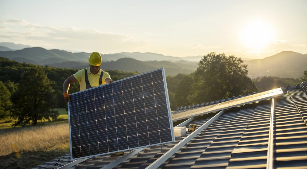 Construction worker fitting solar panel on roof