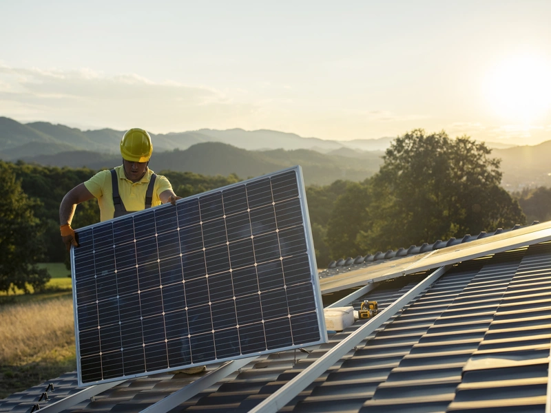 Construction worker fitting solar panel on roof