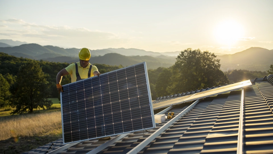 Construction worker fitting solar panel on roof