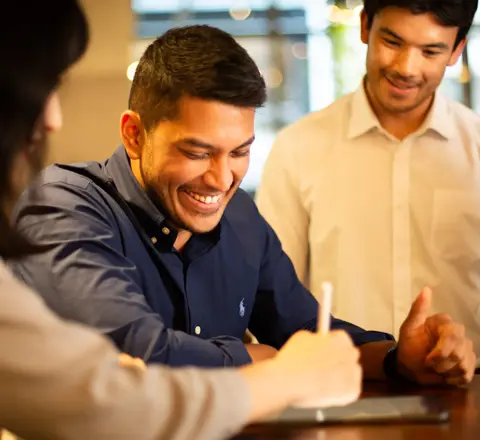 Colleagues together looking at a tablet in a plant-filled a office.