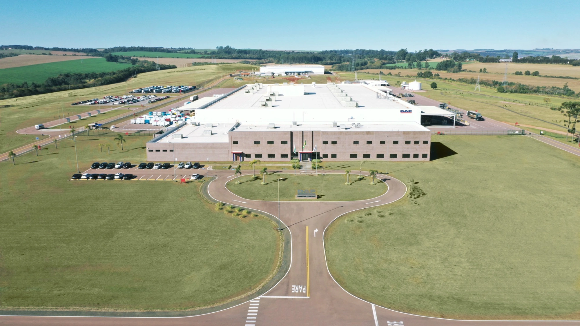 light brown building surrounded by bright green grass, with a pathway leading to the buildings entrance