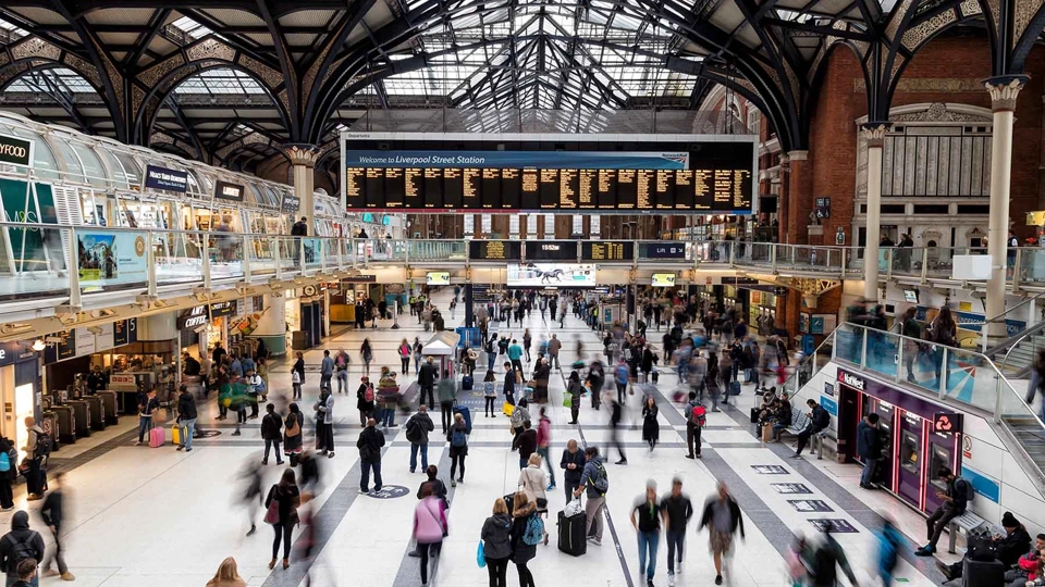 Interior photo of Liverpool Street train station in London, showing dozens of commuters walking through the station's concourse