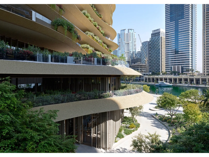 Modern curved building featuring greenery and city skyline in the background