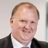 Stuart Scott, Forensic Planning and Delay, smiling in an office, leaning against an orange armchair