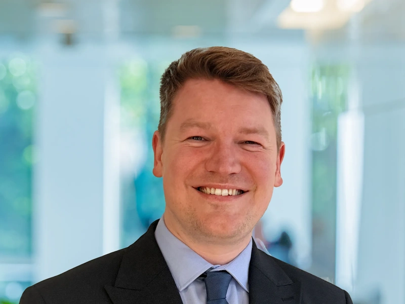 Portrait of Michael O’Connor Atkin, Sports and Venues Lead, Asia, standing in pant based office smiling.