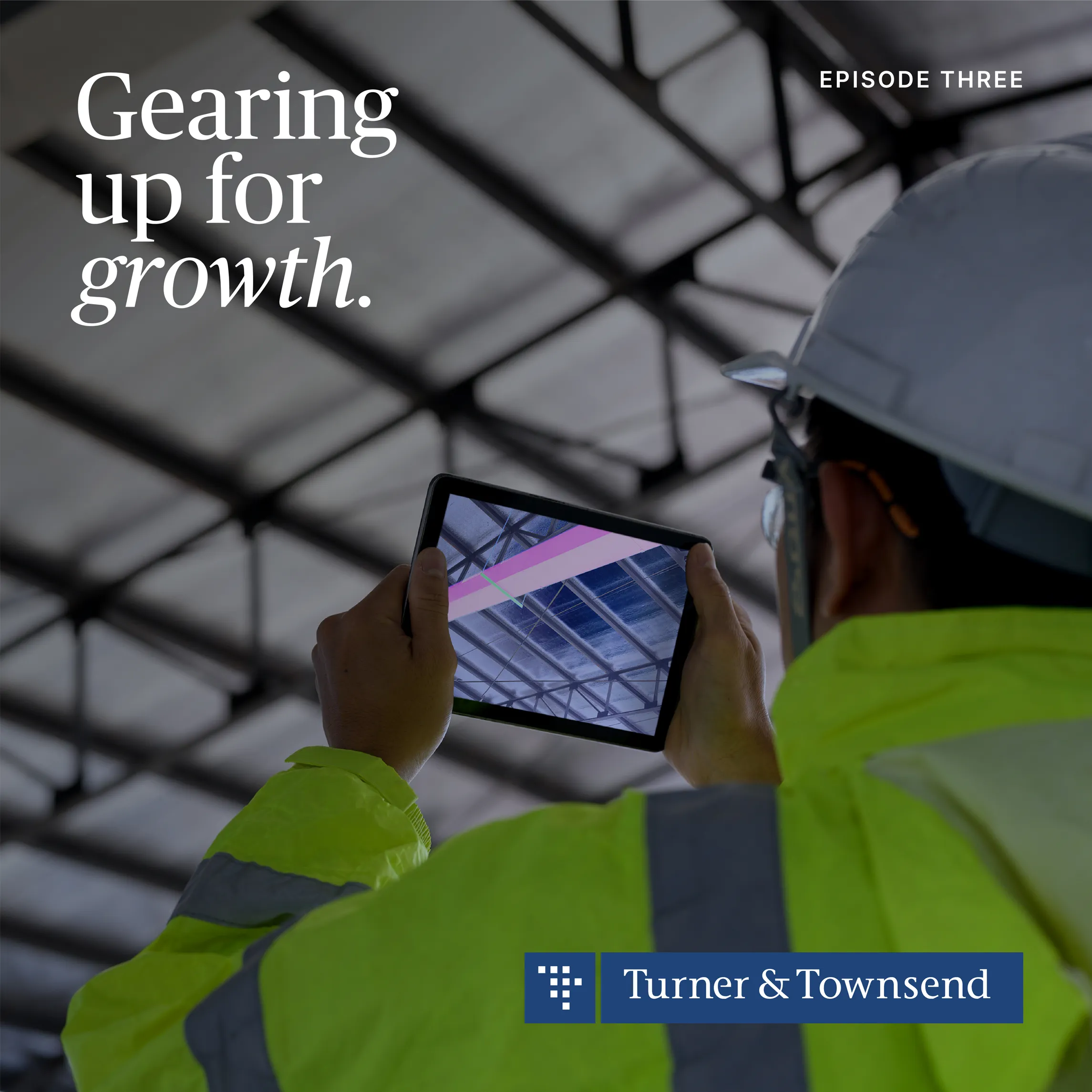 A construction worker in yellow hi vis holding tablet to the ceiling 
