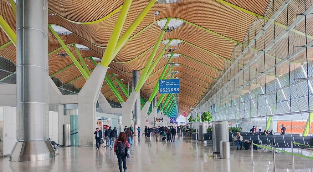Passengers walking through Terminal 4 at Madrid-Barajas airport beneath undulating ceiling