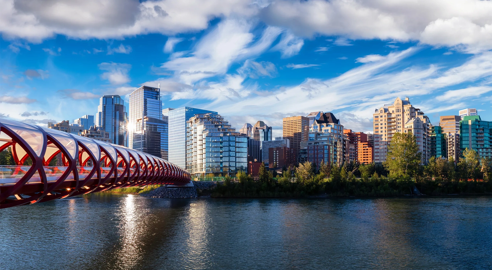 A beautiful sunrise sky over the Peace Bridge and the Bow river in the summertime.