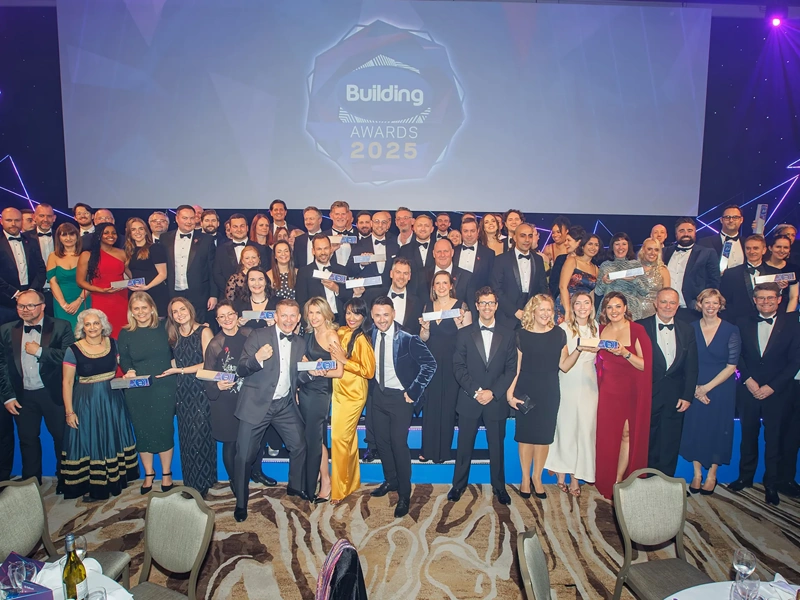 Turner & Townsend winners standing in front of billboard sign smiling at the building awards 2025