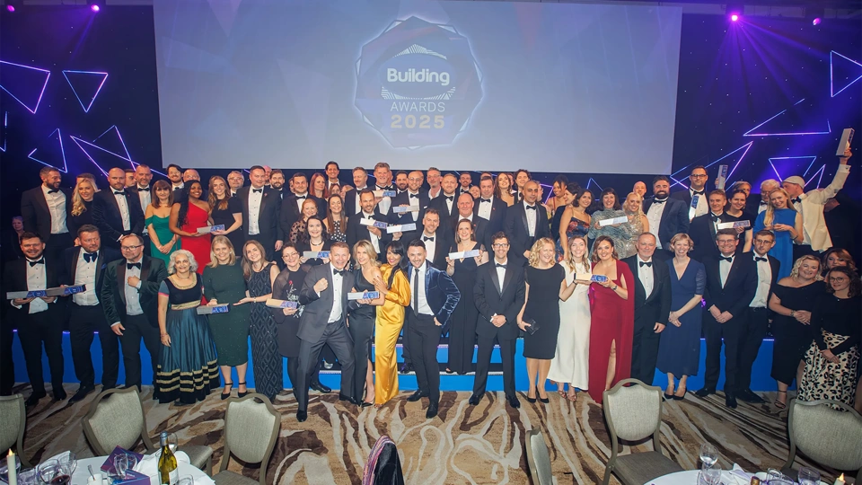 Turner & Townsend winners standing in front of billboard sign smiling at the building awards 2025