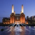 Battersea Power Station lit up at night, view from the Thames with buildings in the background