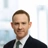 Portrait of Dave Carr, Associate Director, Corporate Occupier, UK, In black suit with green tie against window office.