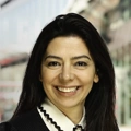 Portrait of Diana Unterstrasser, Director, Europe, Occupier and Retail, standing outside in front of buildings featuring an urban cityscape with a mix of architectural styles. The scene includes some windows and red features, adding a touch of color.