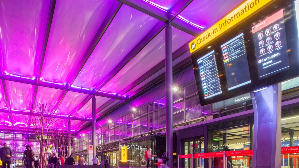 Airport terminal with purple ceiling and check-in information board