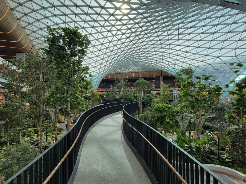 Massive glass dome and elevated walkway above indoor garden at the Orchard at Doha's Hamad International Airport