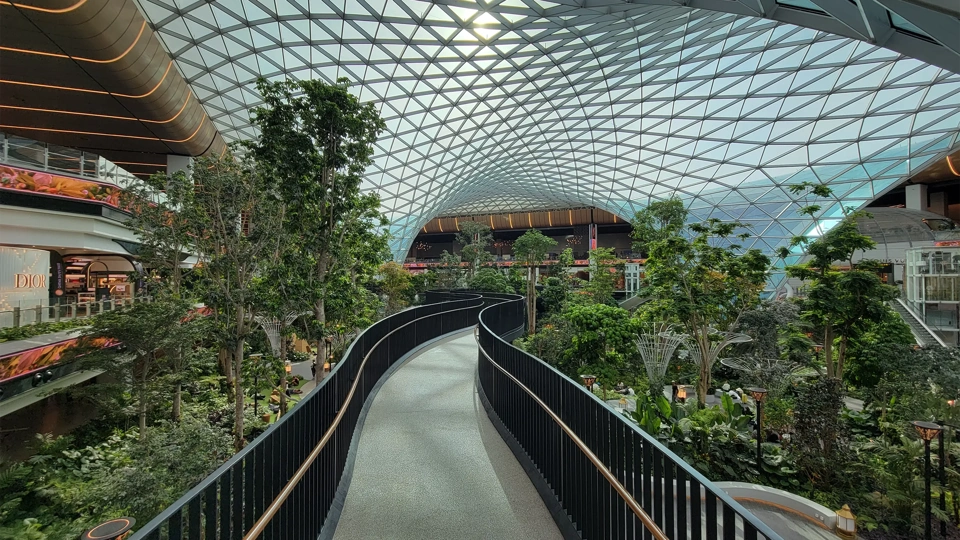 Massive glass dome and elevated walkway above indoor garden at the Orchard at Doha's Hamad International Airport