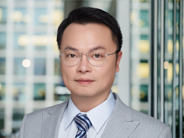 Tino Chang, Lead Director, with city landscape featuring building with lots of windows in the background.