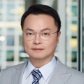 Tino Chang, Lead Director, with city landscape featuring building with lots of windows in the background.