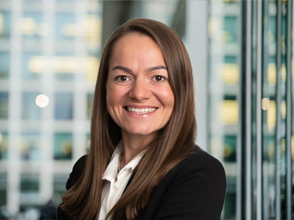 Portrait of Georgina Bishop, Associate Director, Cost Management, with city landscape featuring building with lots of windows in the background.