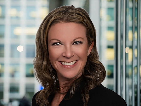 Portrait of Erin Schultz, standing in window based office building smiling.