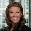 Portrait of Erin Schultz, standing in window based office building smiling.