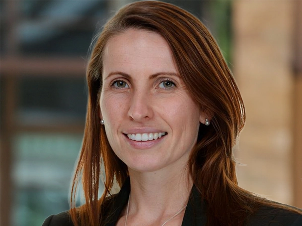 Portrait of Sarah-Jane Finlayson, Director, outside in front of a blurred brown background featuring a building and mix of natural and urban elements.