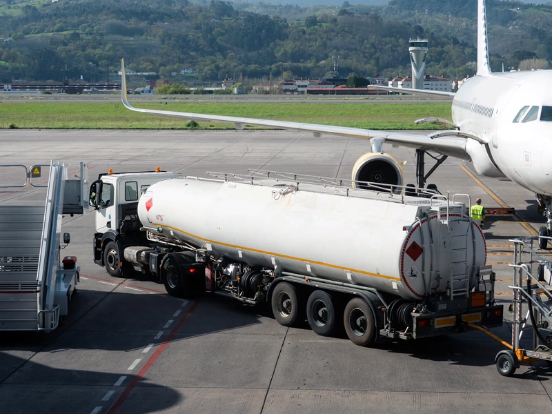 Fuel tanker truck refueling aircraft on airport apron. Concept of aviation fuel logistics, transportation infrastructure and airport operations.