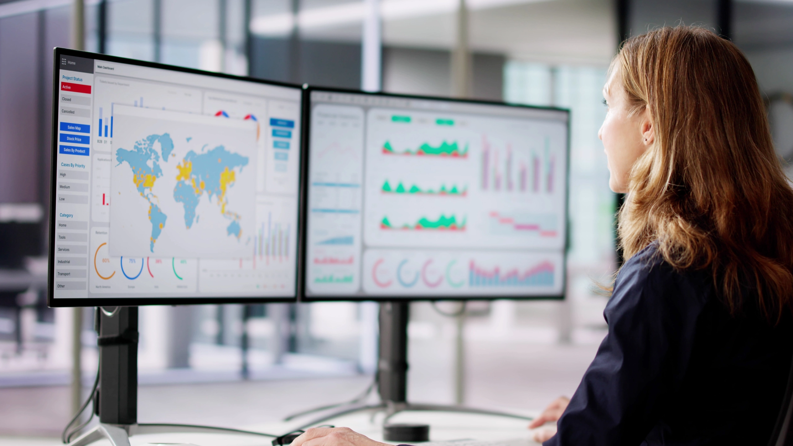 Woman looking at two screens displaying graphs