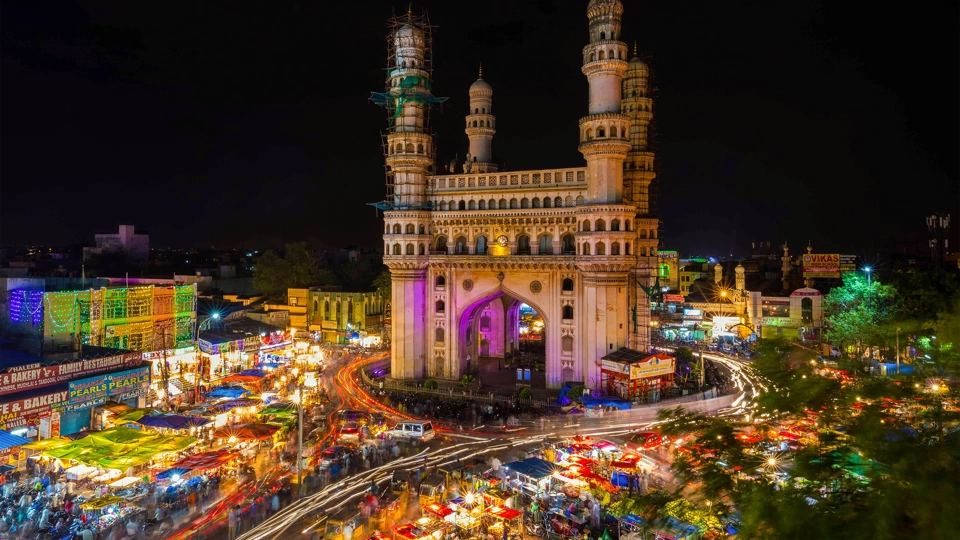 Long-exposure photo of traffic moving around the Charminar monument at night in the city of Hyderabad