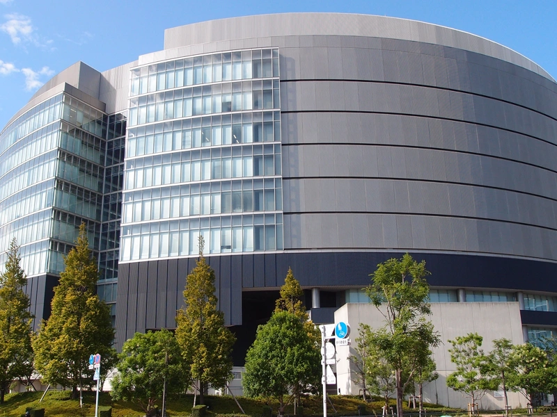 Large grey circular shaped building surrounded by green trees